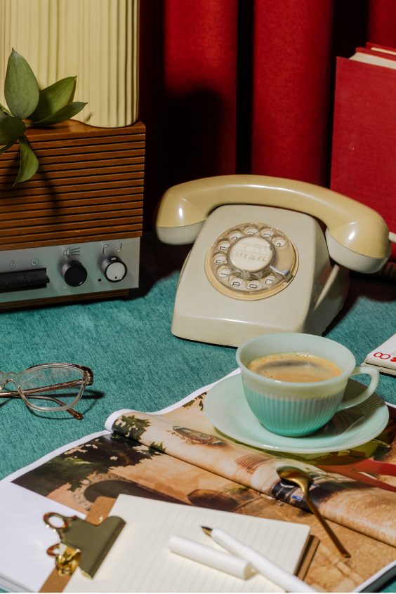 Vintage cream rotary phone with a teacup on a teal desk